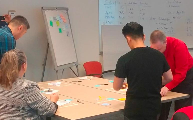 Workshop participants working through a decision-making exercise with sticky notes at a shared table
